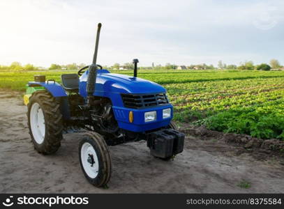 Blue farm tractor stands on field. Application of agricultural machinery in harvesting. Modernization and automation of farm processes. Subsidies and tax refunds for the purchase of new work equipment