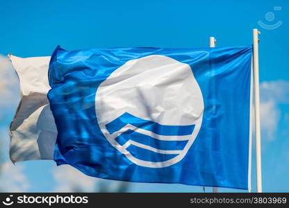 blue flag flying on the beach near the sea