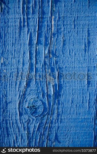 Blue flaky paint on a wood background.