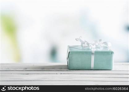 Blue gift box on a wooden table in bright light