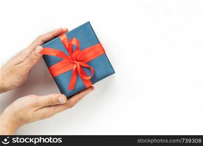 Blue Gift box with red ribbon in womans hands on white background. Top view. Copyspace.. Blue Gift box with red ribbon in womans hands on white background. Top view. Copyspace