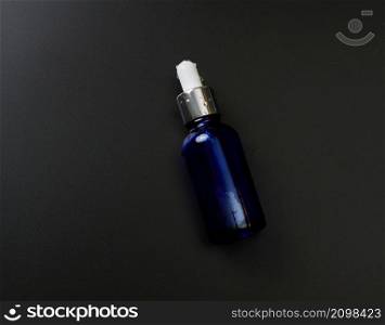 blue glass bottle pipette on a black background. Pharmacy concept. Collagen skin. Mockup skincare cosmetic product