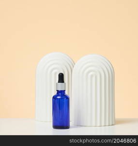 blue glass bottle with pipette stands on a beige background. Cosmetics SPA branding. Packaging for gel, serum, advertising and product promotion