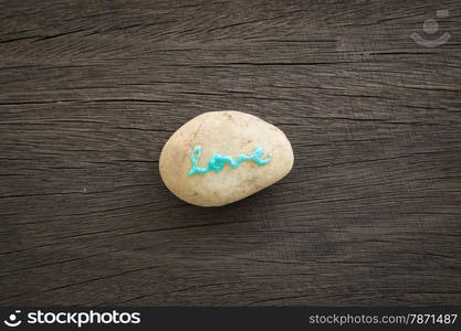 Blue glitter love word on stone place on wood background with vignette, valentine&rsquo;s day symbol