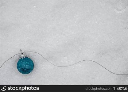 blue glittering Christmas ball with silver thread on snow