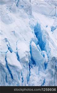 Blue glowing deep gorge in surface of snow and ice glaciers