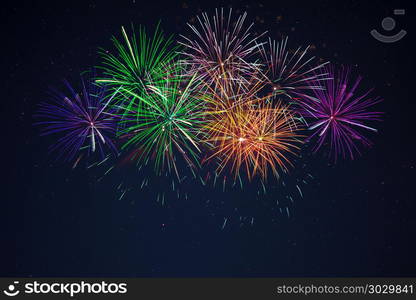 Blue green purple orange fireworks over starry sky. Sparkling blue green purple orange celebration fireworks over starry sky. Independence Day, 4th of July, New Year holidays salute background.