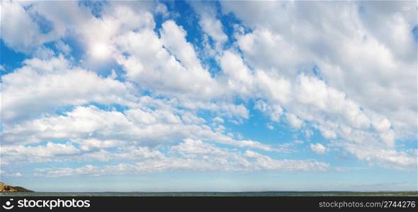 Blue height sky above the sea surface with sun and clouds. Four shots stitch image.
