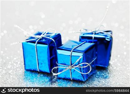 Blue holiday gifts on silver glitter background