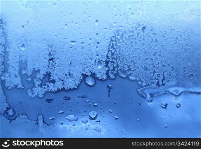 blue ice and water drops on winter glass