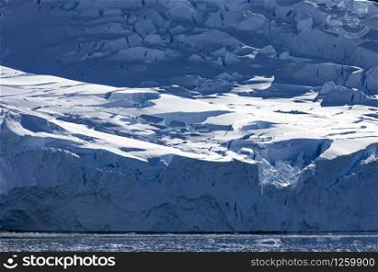 Blue ice from glacier with transition straight to cold sea water in Antarctica