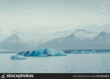 Blue icebergs floating near coast landscape photo. Beautiful nature scenery photography with mountain on background. Idyllic scene. High quality picture for wallpaper, travel blog, magazine, article. Blue icebergs floating near coast landscape photo