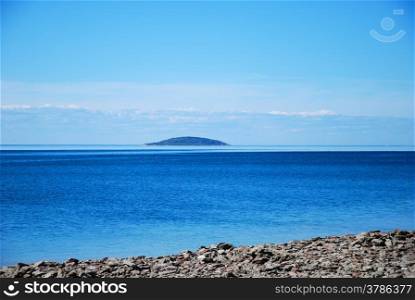 Blue island in blue water by the coast of the swedish island oland in Baltic sea.