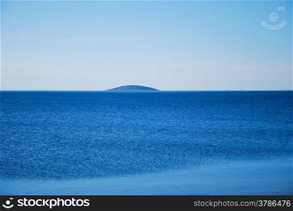 Blue island in blue water by the coast of the swedish island oland in Baltic sea.