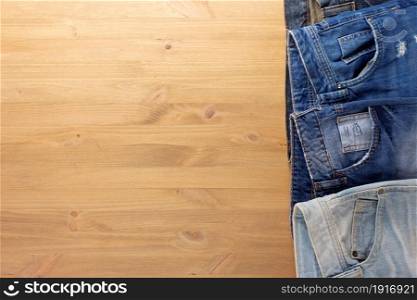 Blue jeans denim on wood table. Jeans heap at wooden background texture