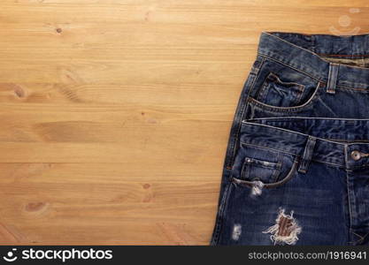 Blue jeans denim pocket on wood table. Jeans heap at wooden background texture