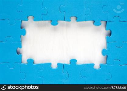 Blue jigsaw puzzle pieces arranged as a border around a wooden surface with space for your text