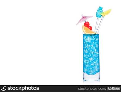 Blue lagoon cocktail highball glass with stirrers and orange slice with sweet cherry and umbrella on white background. Vodka and blue curacao liqueur mix. Space for text