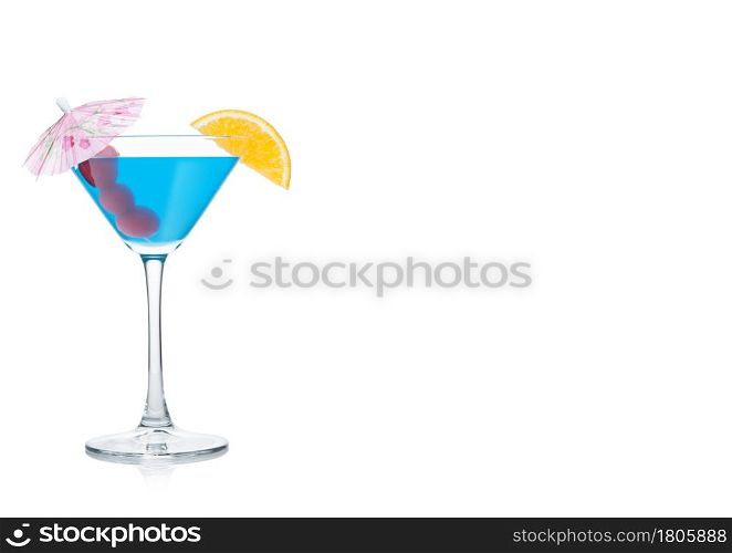 Blue lagoon cocktail in martini glass with orange slice and sweet cherry with umbrella on white background. Space for text