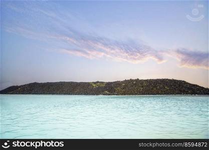 Blue lagoon with turquoise water in the sunset with large lava cliffs in the background