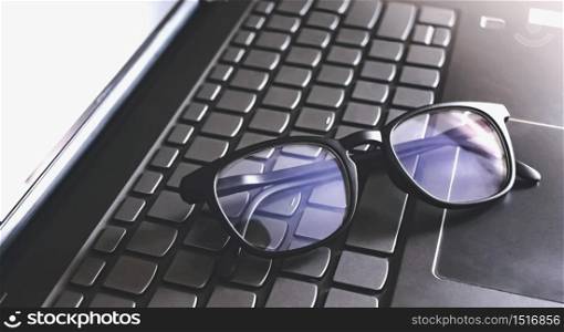 blue light blocking glasses on the keyboard button of computer laptop. working or learning online.
