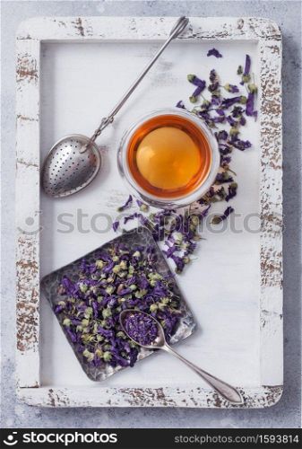 Blue mallow flowers herbal tea with vintage strainer infuser in wooden box on white table background. Top view
