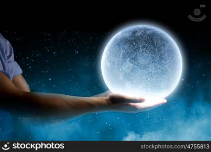 Blue moon. Close up of human hand holding blue glowing moon