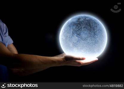 Blue moon. Close up of human hand holding blue glowing moon