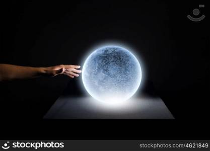 Blue moon. Close up of human hand touching blue glowing moon