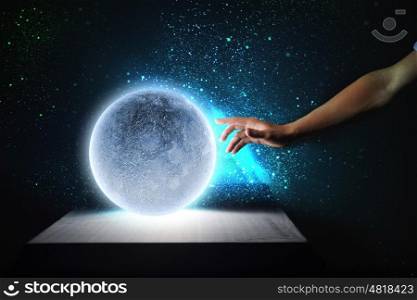 Blue moon. Close up of human hand touching blue glowing moon