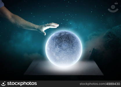 Blue moon. Close up of human hand touching blue glowing moon