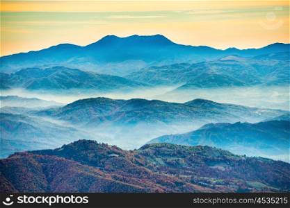 Blue mountains at sunset with white mist over hills