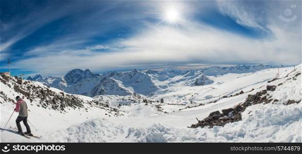 Blue mountains in snow with clouds. Panorama with skier