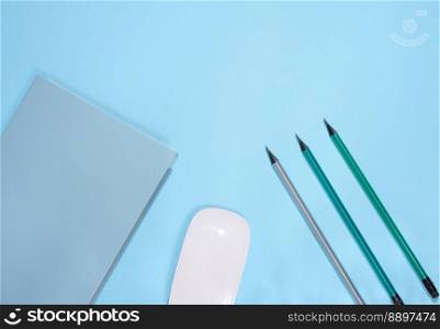 Blue notepad and wooden pencil on a blue background, top view