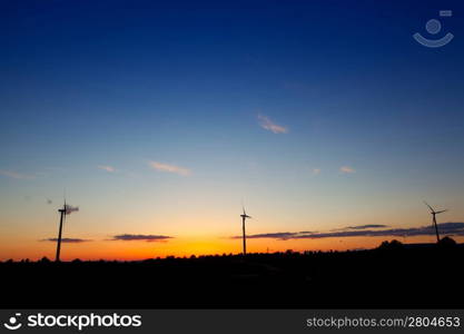 Blue orange sunset with electric windmills aerogenerators