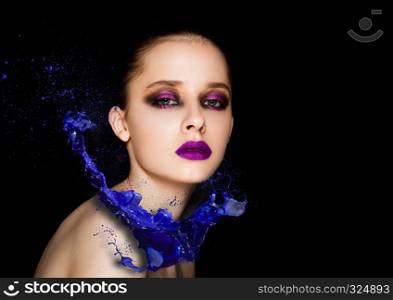 Blue paint splash over beauty makeup fashion model girl with purple smokey eyes abstract on black background