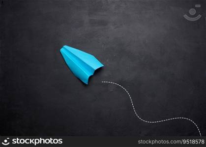 Blue paper airplane on a black background, travel concept, top view. Copy space