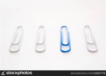 Blue paper clip with collection of white ones.