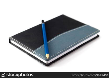 Blue pencil on black leather moleskin notebook on white.