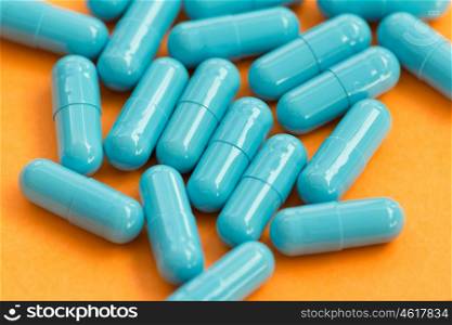 Blue pills on orange background. Medicines to heal