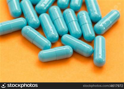 Blue pills on orange background. Medicines to heal