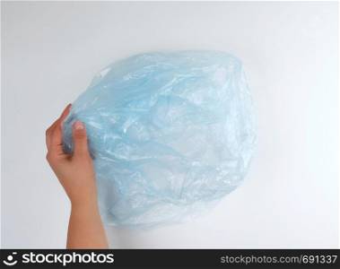 blue plastic garbage bag in female hand on a white background, top view