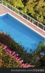 Blue Pool In The Summer Sun With Flowers On The Side