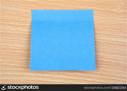 Blue post-it stuck on a wooden surface