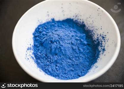 blue powder inside white bowl black background