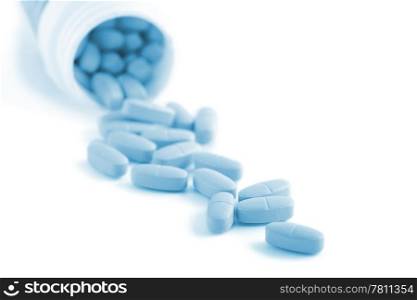 blue prescription pills falling out of bottle isolated
