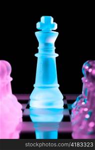 blue queen and rows of purple glass chess pawns is standing on board in dark