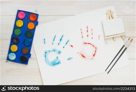 blue red hand print white sheet with painting equipment wooden surface