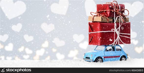 Blue retro toy car delivering heart for Valentine's day on gray background