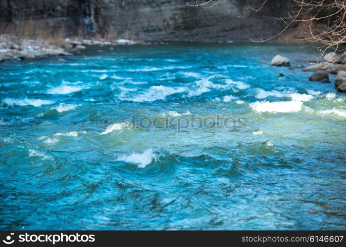 Blue river water with waves streaming near banks